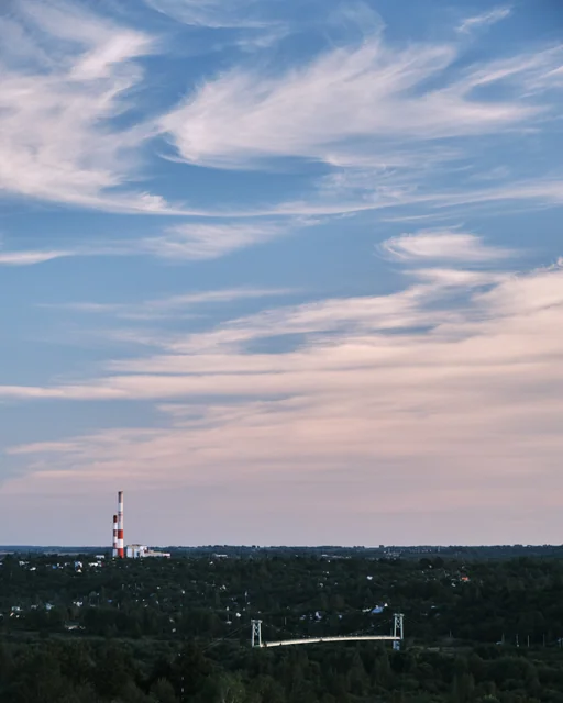 Pink and blue streaks of cloud above a distant city skyline.