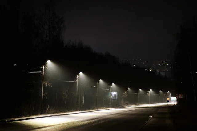 A row of streetlights follows a dark road with long trails of white light.