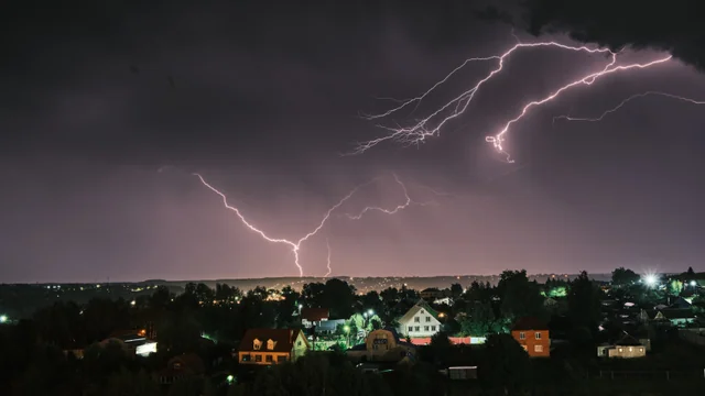 Forks of lightning illuminate a storm over the city at night.