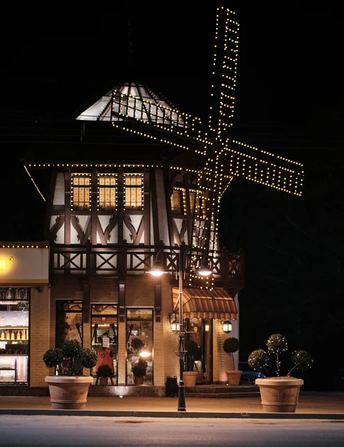 A windmill-shaped building outlined with warm string lights at night.